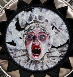 a close up of a face made out of beads and sequins on a plate