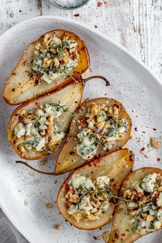 four pears with cheese and nuts on a white plate