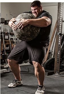 a man holding a large ball in a gym