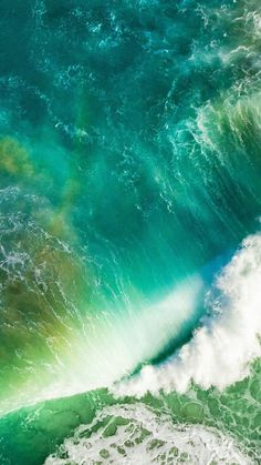 an aerial view of the ocean with green and blue waves