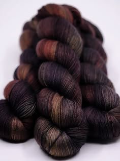 several skeins of yarn are stacked on top of each other in shades of brown and black