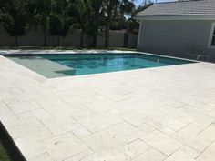 an empty swimming pool in a backyard with grass and trees around it, next to a house