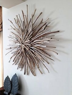 a sunburst made out of driftwood is mounted on the wall next to a vase