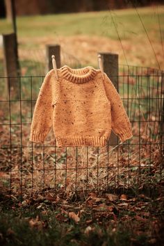 an orange sweater hanging on a wire fence