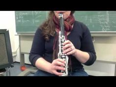 a woman sitting in front of a blackboard playing a flute