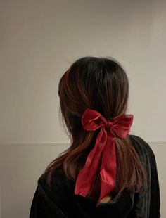 the back of a woman's head with a red bow in her hair,