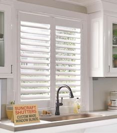 a kitchen window with white shutters and a sign that reads suncat shutters outside the window blinds