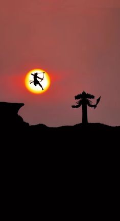 the sun is setting behind a silhouette of a tree and a person jumping in the air