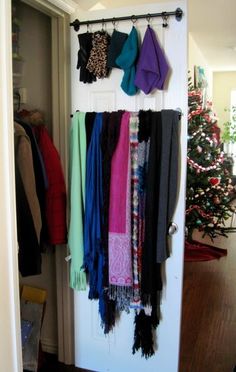 an open closet with clothes hanging on the door and a christmas tree in the background