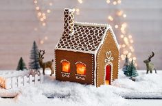 a gingerbread house is lit up in the snow