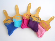 five pairs of socks hang from wooden clothes pegs on a white surface with the words socks printed on them