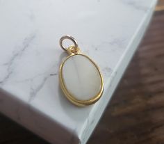 oval shaped mother of pearl with gold frame.  4mm jump ring pendant size 20x11mm Classic White Oval Pendant Jewelry, White Oval Pearl Pendant Jewelry, White Cabochon Mother Of Pearl Jewelry, White Cabochon Oval Pendant Jewelry, White Pearl Charm Jewelry, White Oval Jewelry With Pearl Charm, White Mother Of Pearl Cabochon Jewelry, Handmade White Jewelry With Oval Cabochon, Elegant Oval White Jewelry With Mother Of Pearl