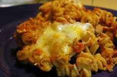 a blue plate topped with macaroni and cheese covered in melted cheesy sauce