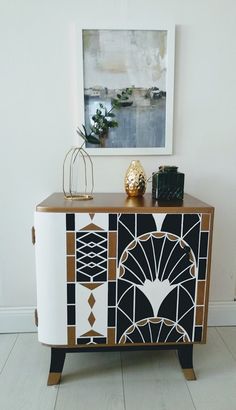 a black and white cabinet with geometric designs on it next to a gold candle holder