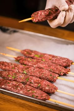 a person is cooking meat on skewers with chopsticks