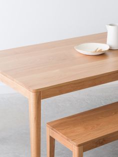 a wooden table with a white plate on it and a bowl sitting on top of it