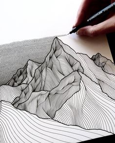 someone is drawing mountains on paper with a pen