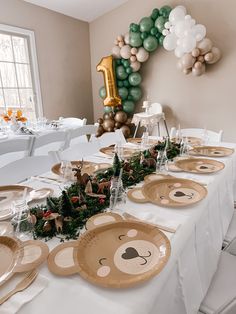 the table is set with plates and place settings for an animal themed birthday party at home