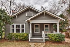 a gray house with white trim on the front porch and steps leading up to it