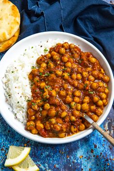 a white bowl filled with chickpeas and rice next to a lemon wedge on the side