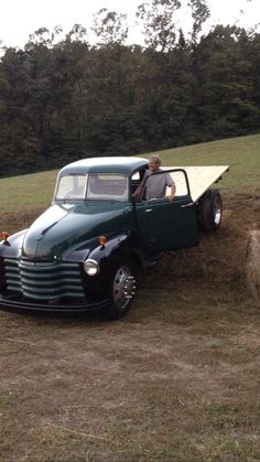 an old pick up truck is parked on the side of a hill with a man sitting in it