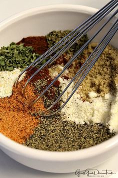 a bowl filled with spices and seasoning next to a whisk