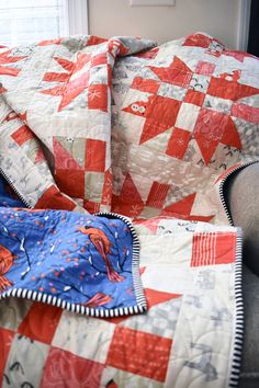 a red and white quilt on a chair with a blue blanket draped over the couch