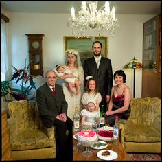 a family posing for a photo in their living room with cake and wine on the table