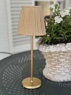 a lamp sitting on top of a table next to a potted plant with white flowers