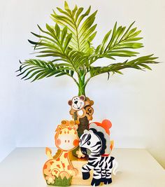 a plant in a vase with animals on it and a zebra figurine next to it