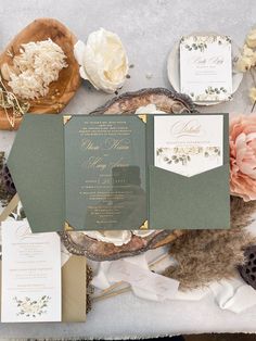 the wedding stationery is laid out on a table with flowers and other items around it