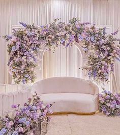 a white couch sitting under a purple flower covered arch