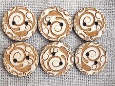 four wooden buttons with swirl designs on them