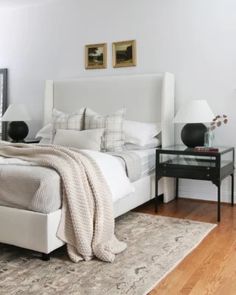 a white bed sitting in a bedroom on top of a hard wood floor next to a window