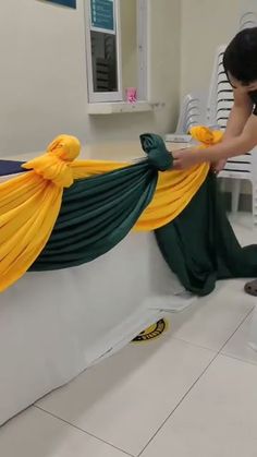 a woman sitting on top of a white toilet next to a green and yellow curtain