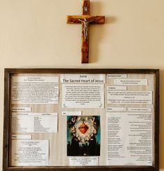 a cross mounted to the side of a wall next to a bulletin board with information about jesus