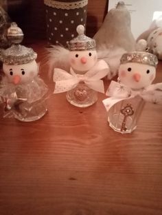 three snowmen are sitting next to each other on a table with some glass containers