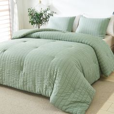 a bed with green comforter and pillows in a room