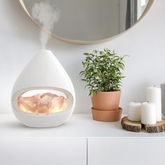 an air humider sitting on top of a white counter next to a potted plant