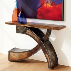 a wooden table with two vases sitting on it's shelf next to a painting