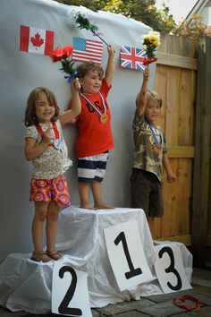 two young children standing on top of a podium with their hands up in the air