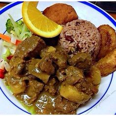 a white plate topped with meat, rice and veggies next to an orange slice