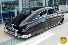 an old black car parked in front of a building