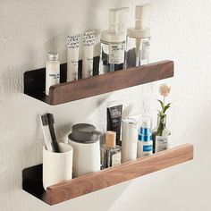 two wooden shelves holding various personal care items and toothbrushes on the wall behind them