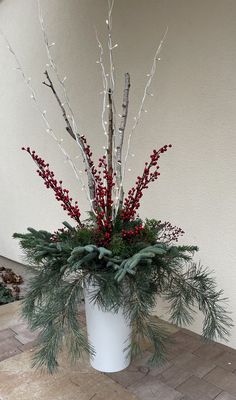 a white vase filled with red berries and greenery on top of a tiled floor