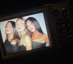 three women are posing in front of a television screen with the same image on it