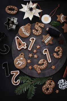 gingerbread cookies decorated with icing and christmas decorations on a black plate surrounded by other holiday items