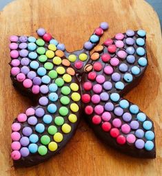 a chocolate butterfly decorated with candy on top of a wooden cutting board