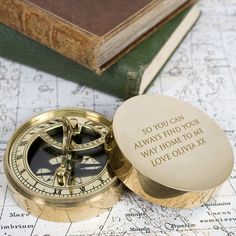 a brass compass sitting on top of a map next to a book and some books