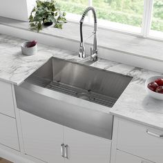 a stainless steel kitchen sink with marble countertops and drawers in front of a window